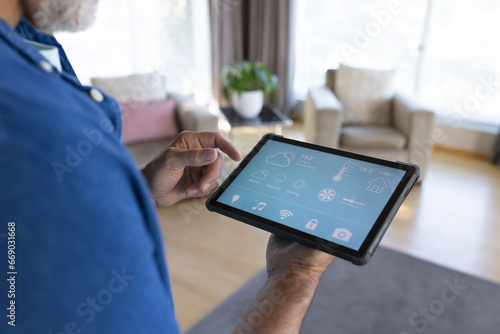 Midsection of senior caucasian man using tablet with smart home interface