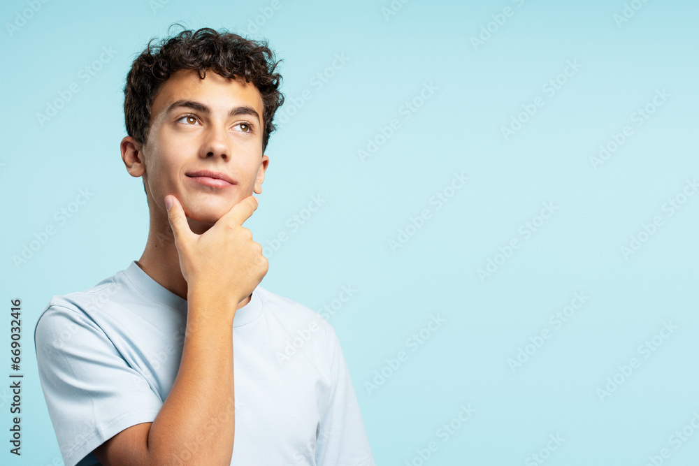 Portrait of smart pensive school boy with curly hair looking for solution isolated on blue background, copy space. Education concept Portrait of smart pensive school boy with curly hair looking for solution isolated on blue background, copy space. Education concept