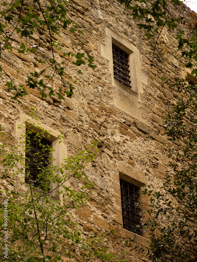 fenêtre à fer forgé en façade du mur d'un château avec pierres apparentes fenêtre à fer forgé en façade du mur d'un château avec pierres apparentes