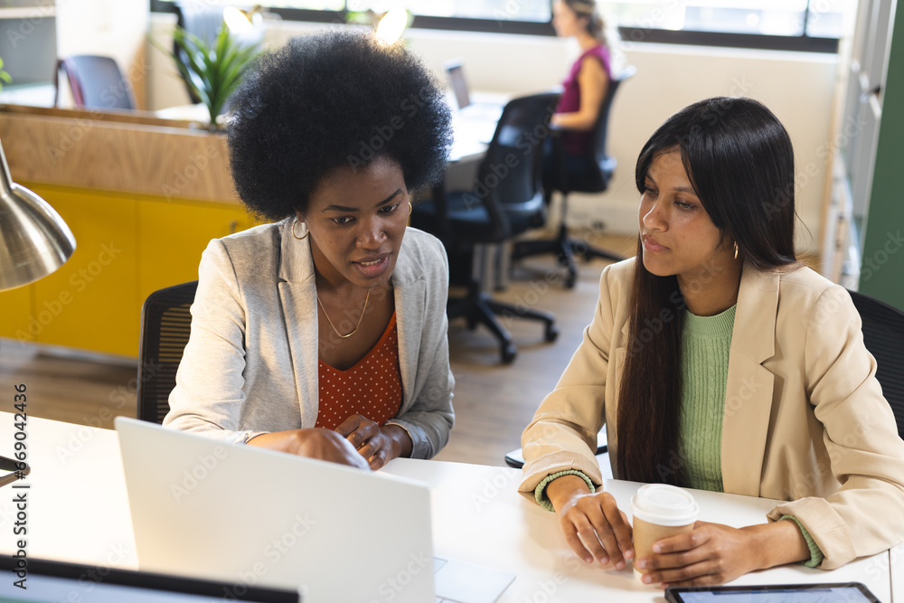 Busy diverse female colleagues discussing work with laptop in office Busy diverse female colleagues discussing work with laptop in office