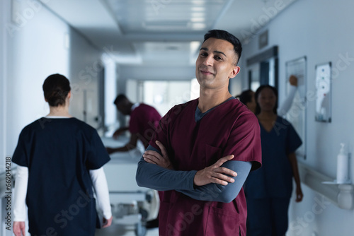 Portrait of happy biracial male doctor wearing scrubs in hospital photo