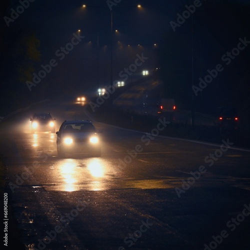 Cars on the road in the fog. Autumn and winter concept of dangerous traffic in bad weather. Car lights in bad visibility.