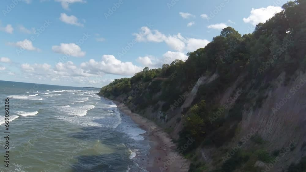 FPV drone flying over trees near wavy ocean with foamy water washing sandy beach on sunny summer day FPV drone flying over trees near wavy ocean with foamy water washing sandy beach on sunny summer day