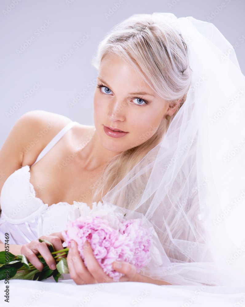 Portrait, woman and bride with bouquet, lingerie and beauty with celebration on a white studio background. Person, model and girl with flowers, underwear and veil with plants, luxury and marriage