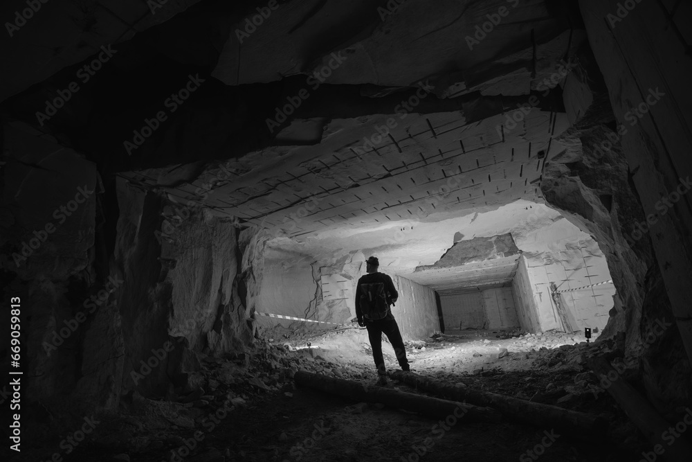 A man with powerful flashlights explores dangerous tunnels, old abandoned quarry mines near the