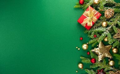 Beautiful green Christmas background with a border of fir branches, golden Christmas toys, stars and gifts. New Year's decoration for congratulations.
