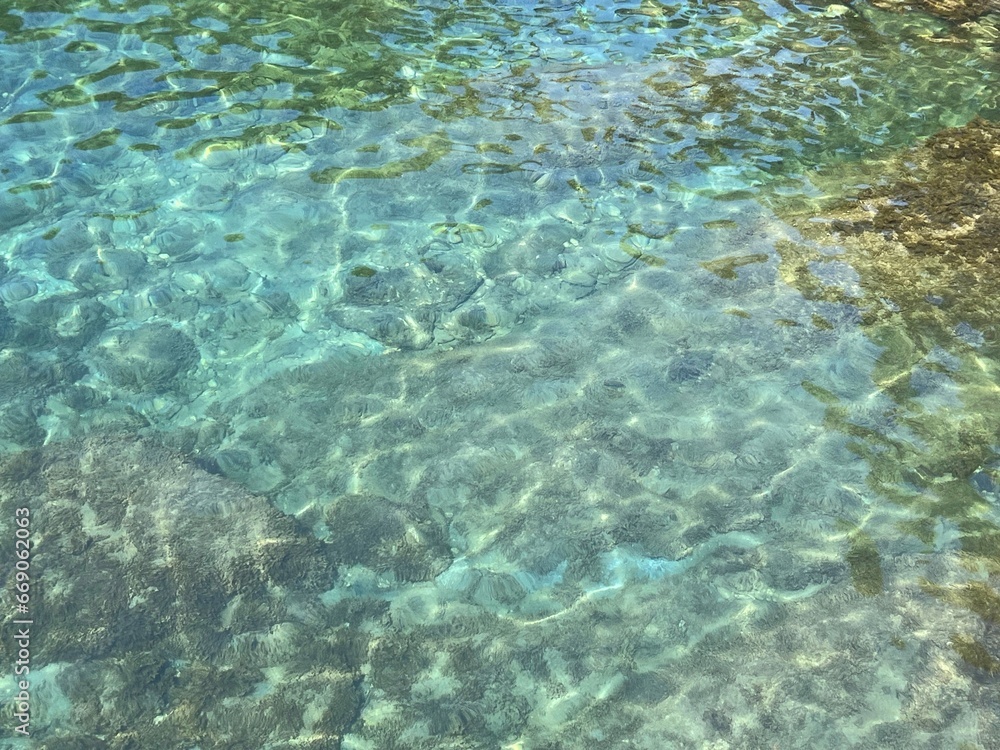 Sea crystal clear water surface with stones and algae at the bottom. 