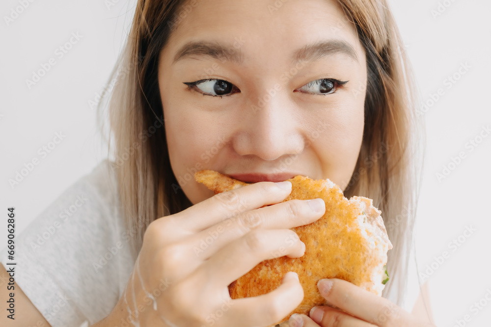 Close up of Thai woman eating and having homemade sandwich breakfast alone while thinking something. Close up of Thai woman eating and having homemade sandwich breakfast alone while thinking something.