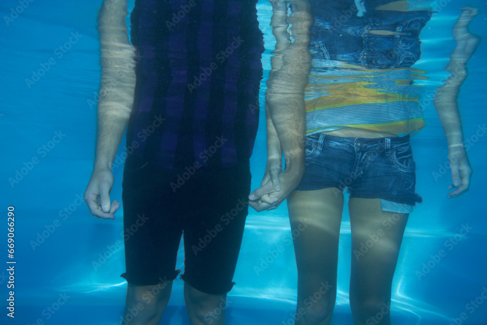 Couple, clothes or underwater swimming pool or fashion, trendy style or holding hands. Male person, woman or relationship fun cool outfits for summer look or holiday, romantic or playful wet t-shirt - obrazy, fototapety, plakaty 