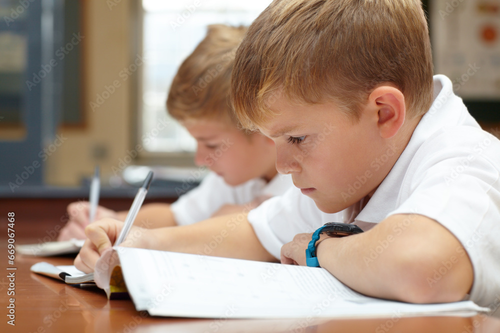 Young students, classroom and writing in books for education, thinking mindset or children on scholarship. Boys, school kids or learning with creative idea on desk, studying and test or work in class Young students, classroom and writing in books for education, thinking mindset or children on scholarship. Boys, school kids or learning with creative idea on desk, studying and test or work in class