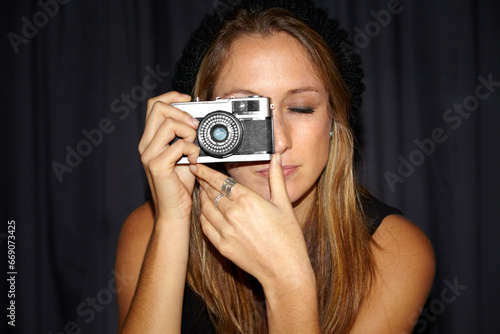 Woman, vintage camera and photographer in dark background, picture and hipster. Serious, youth and hobby with photography, perspective planning and eyes closed, creative and cool with mockup space © Tylan Elliott/peopleimages.com