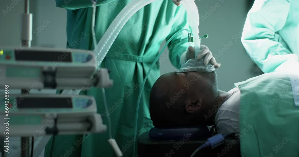 Surgeon using anaesthetic mask on african american male patient in operating theatre, slow motion Surgeon using anaesthetic mask on african american male patient in operating theatre, slow motion
