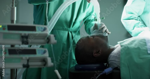 Surgeon using anaesthetic mask on african american male patient in operating theatre, slow motion