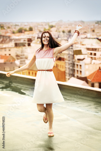 Woman, arms and happy on rooftop for travel, adventure and freedom on trip to Croatia, cityscape and sky. Female person, vacation and happy or positive for getaway, energy and stretching in holiday