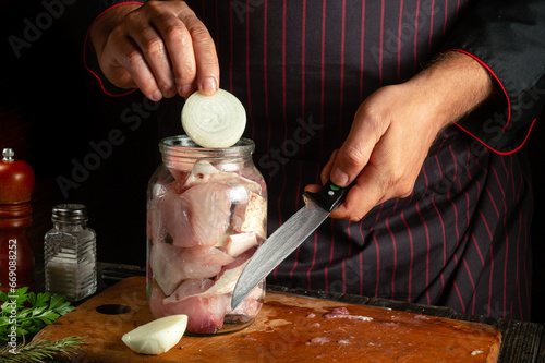 The cook prepares salted fish in a jar. The concept of salting or canning fish at home with spices and onions photo