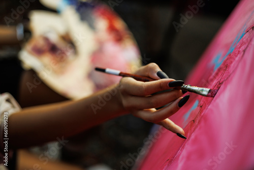 Close up of african american artist painting on canvas and holding blurred palette in workshop