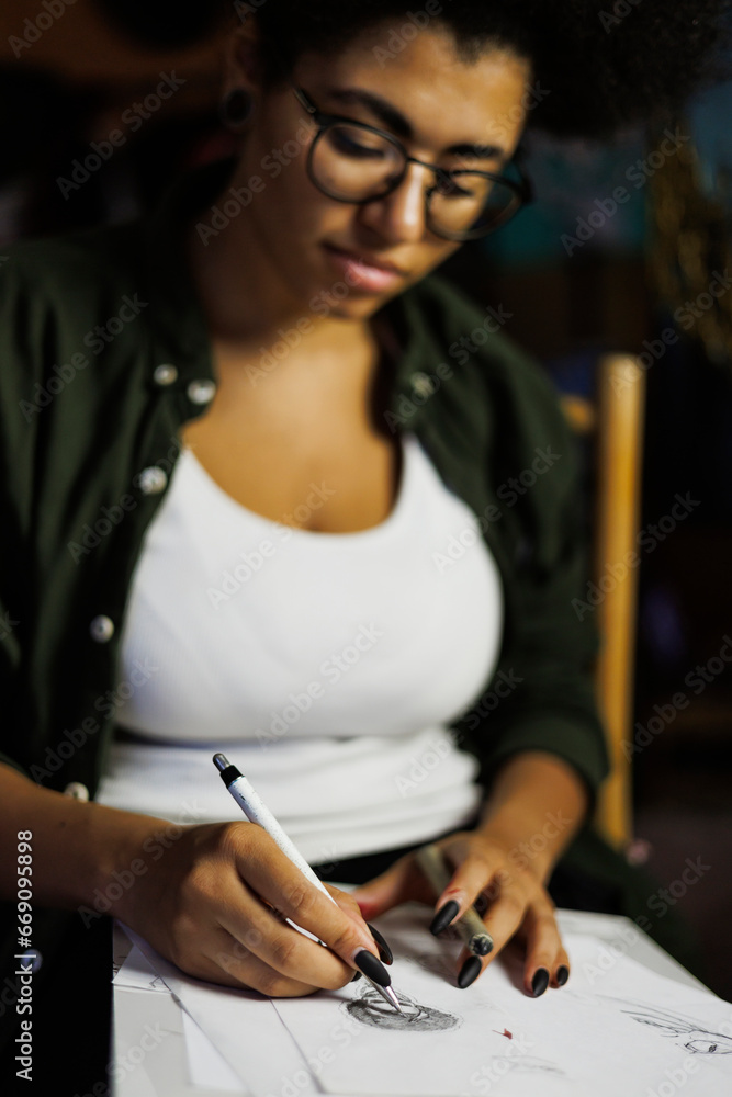 Blurred african american artist drawing on sketchbook in studio in evening Blurred african american artist drawing on sketchbook in studio in evening
