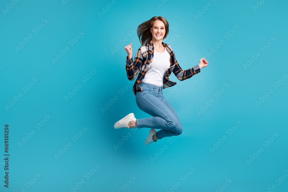 Full body portrait of young excited jumping woman isolated blue color background