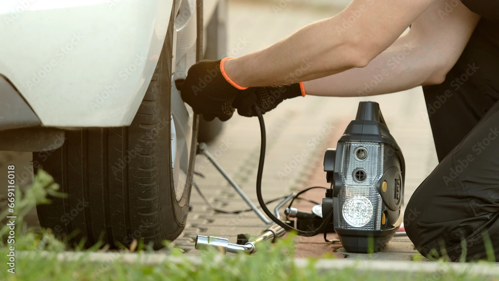 Man Inflates Tire With Portable Pump As Mechanic Man Inflates Tire With Portable Pump As Mechanic