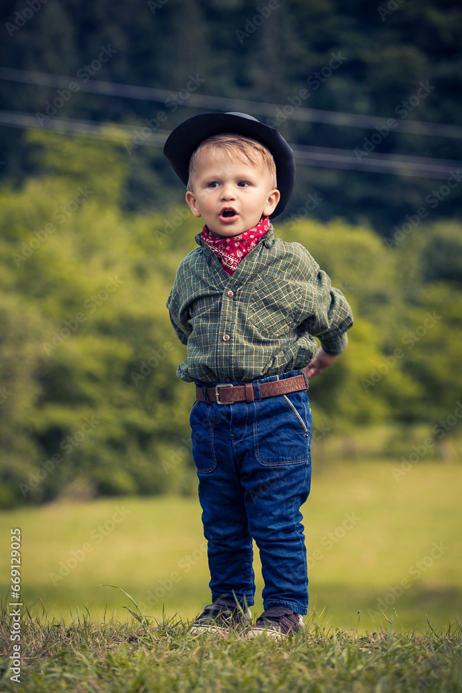 Cute Toddler in Cowboy Suit with Hat and Jeans Smiling in Outdoor Nature Cute Toddler in Cowboy Suit with Hat and Jeans Smiling in Outdoor Nature