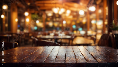 A wooden table in a restaurant or bar. The table is in the foreground and in the background is an area with wooden chairs and tables and pendant lights. The background is blurred photo
