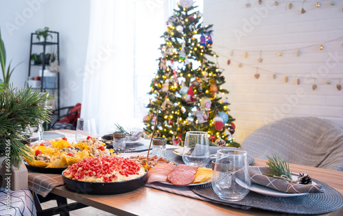 Serving a festive table with snacks, salads and goodies close-up in the modern interior of a loft house decorated for Christmas and New Year. Waiting for guests for a festive dinner