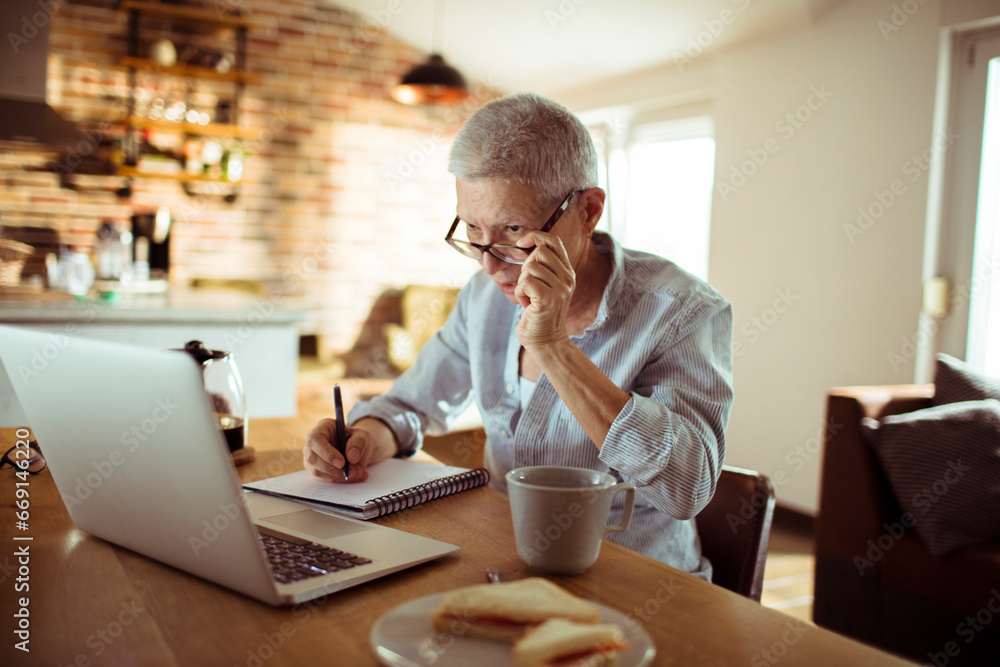 Senior woman working from home and taking notes