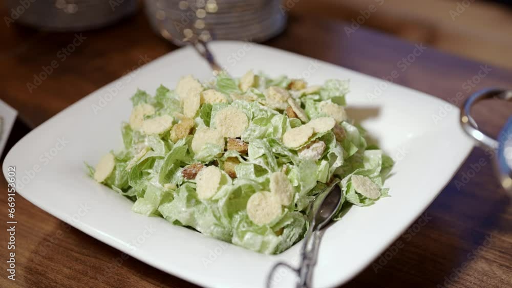 A close-up shot of a Caesar salad with croutons and parmesan cheese The salad is made with romaine lettuce, croutons, parmesan cheese, and Caesar dressing A close-up shot of a Caesar salad with croutons and parmesan cheese The salad is made with romaine lettuce, croutons, parmesan cheese, and Caesar dressing