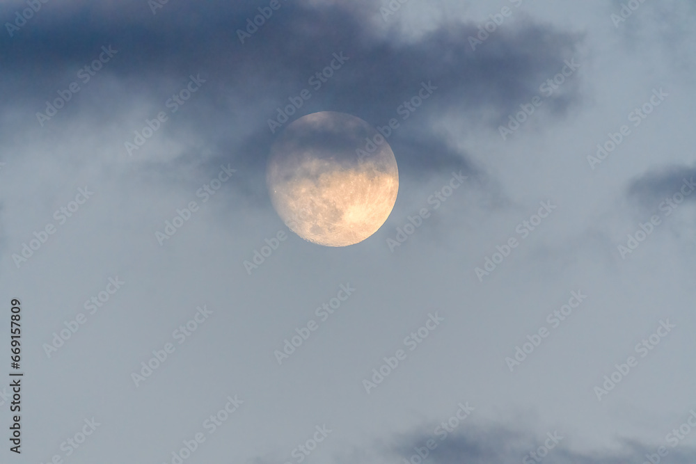 Closeup of Golden Moon in Gray Cloudy Sky at Sunset 