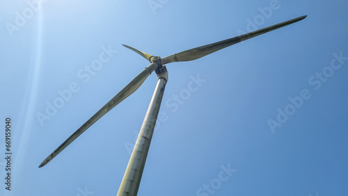 close view of wind turbine with three blades and clear blue sky in background © Vaishuren