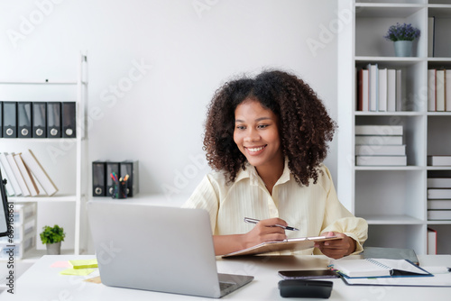 African American businesswoman sitting at the desk in front of the laptop and thinking. © PaeGAG