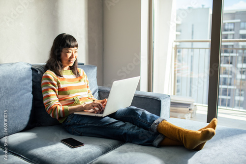 Japanese woman working comfortably on her laptop at home photo