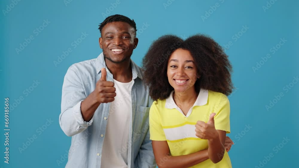 Joyful African-American man and woman show thumbs up Joyful African-American man and woman show thumbs up