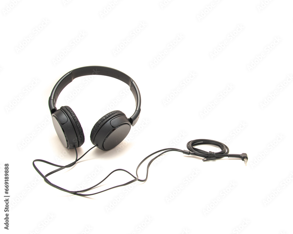 Top view black wired headphone with swiveling earcup foam cushions, L-shaped stereo mini plug 3.5mm isolated on white background, corded kids headphones, technology accessories Top view black wired headphone with swiveling earcup foam cushions, L-shaped stereo mini plug 3.5mm isolated on white background, corded kids headphones, technology accessories