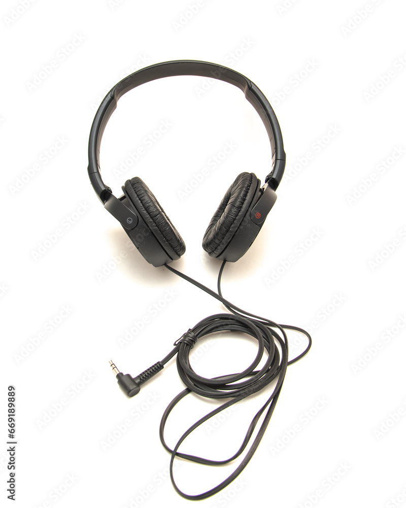 Side view black wired headphone with swiveling earcup foam cushions, L-shaped stereo mini plug 3.5mm isolated on white background, corded kids headphones dome type Side view black wired headphone with swiveling earcup foam cushions, L-shaped stereo mini plug 3.5mm isolated on white background, corded kids headphones dome type