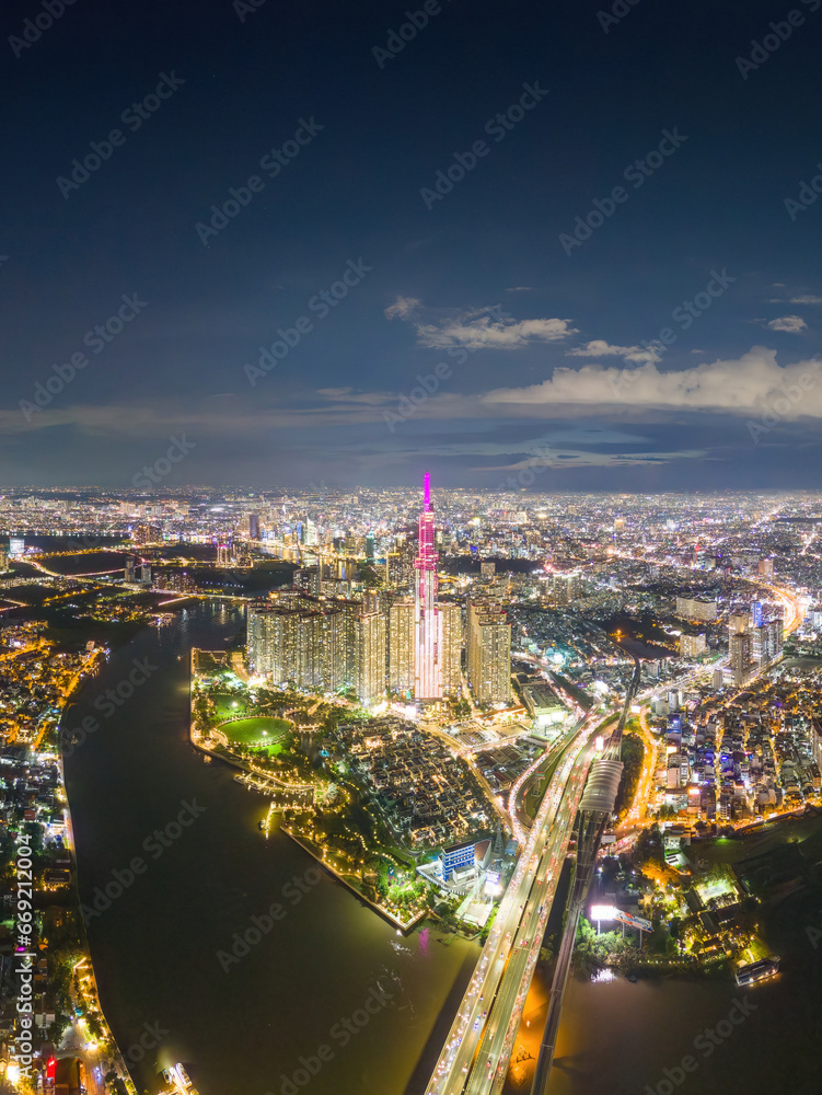 Fototapeta premium Aerial sunset view at Landmark 81 - it is a super tall skyscraper and Saigon bridge with development buildings along Saigon river, cityscape in the night