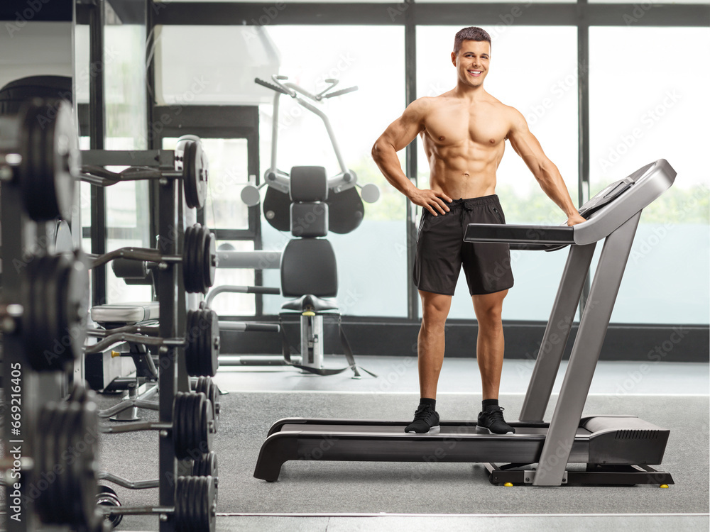 Fototapeta premium Full length shot of a bodybuilder posing on a treadmill at the gym