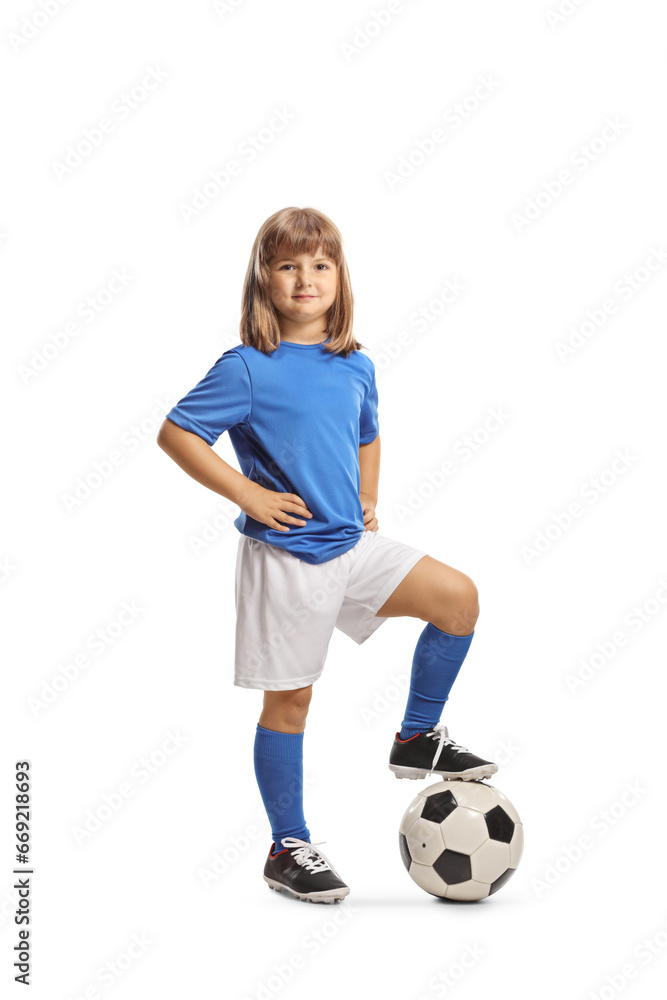 Smiling little girl in sports jersey standing with foot on top of a football