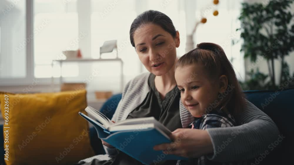 Kind mother reading fairytale to little smiling daughter, care and parenting Kind mother reading fairytale to little smiling daughter, care and parenting