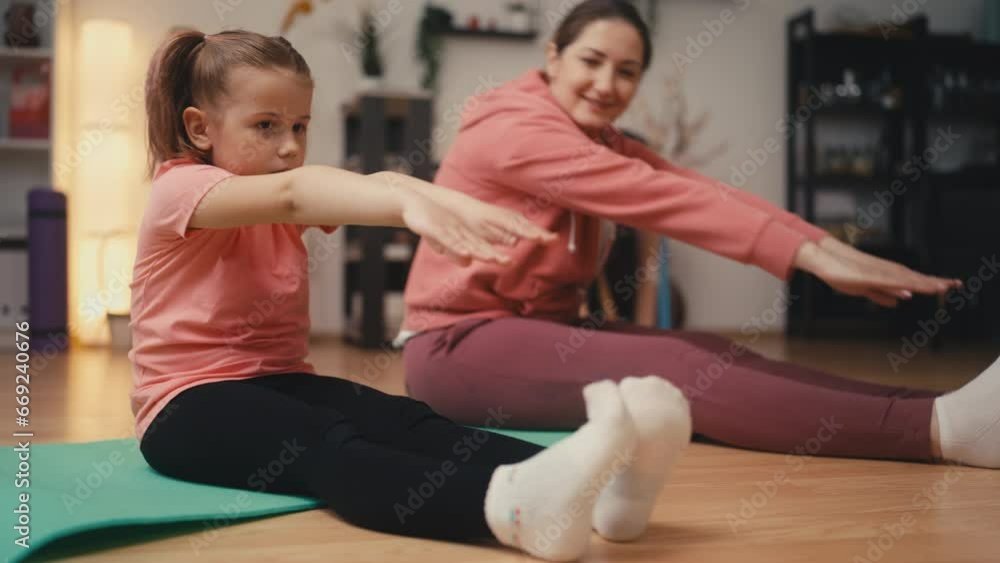 Happy mom and little daughter doing fitness and stretching exercises at home Happy mom and little daughter doing fitness and stretching exercises at home