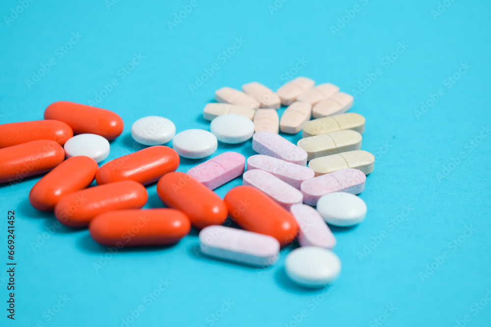 Colorful Medicine Pills in heart shape isolated on blue background, supplement, vitamin, colorful
