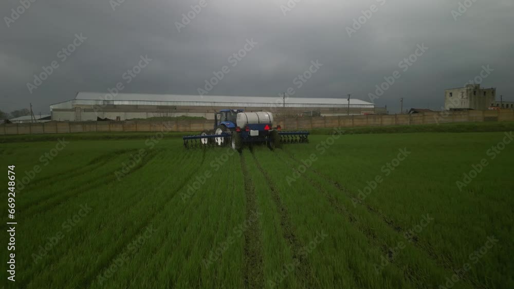 Blue tractor on the field doing liquid fertilizer injection Blue tractor on the field doing liquid fertilizer injection