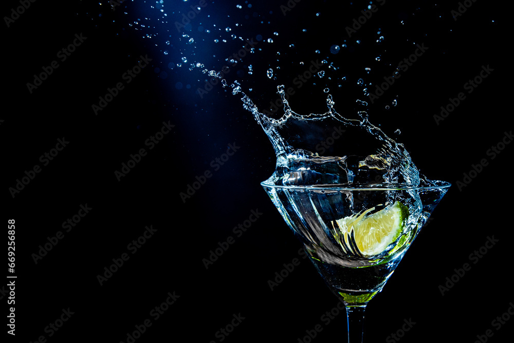 splash in a glass with lime slice on a black background splash in a glass with lime slice on a black background
