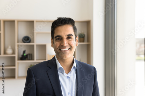 Happy handsome Indian businessman in formal suit looking at camera with toothy smile. Positive top manager, executive, CEO, entrepreneur, business professional head shot portrait photo