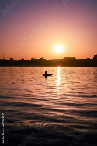 Lonely fisherman on a boat on the river at sunset