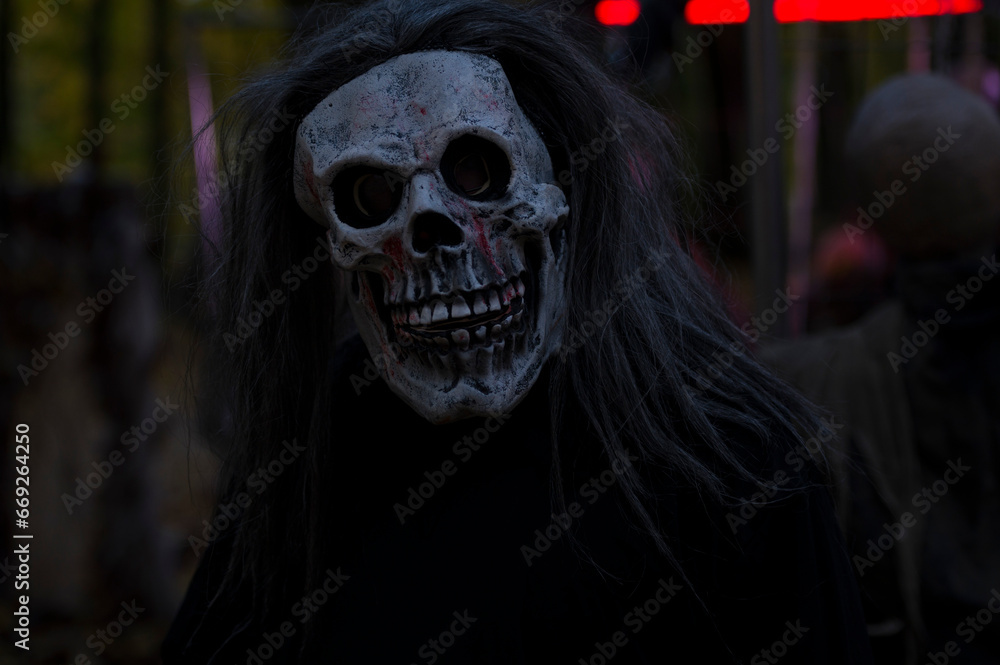 Halloween decoration, grinning clown standing on ghosts background in the forest Halloween decoration, grinning clown standing on ghosts background in the forest