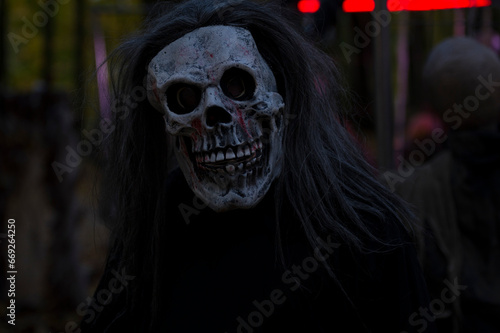 Halloween decoration, grinning clown standing on ghosts background in the forest