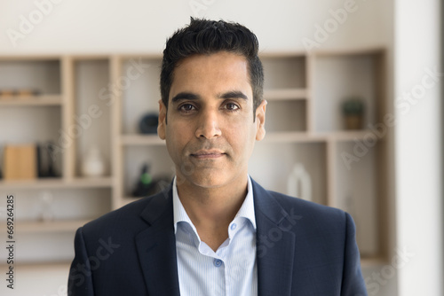 Serious handsome Indian executive man in formal cloth head shot portrait. Positive middle aged businessman, business professional, CEO, entrepreneur looking at camera, posing in office