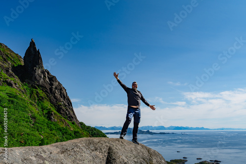 Man adventurer Norway Travel hiking lifestyle concept active weekend summer vacations. Life on the edge Traveler on cliff mountains over fjord enjoying Norway landscape. active healthy lifestyle