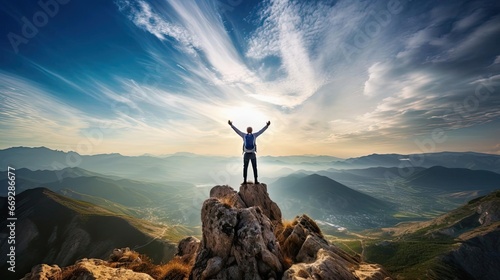 A man stands on the top of a mountain with his hands raised © cherezoff
